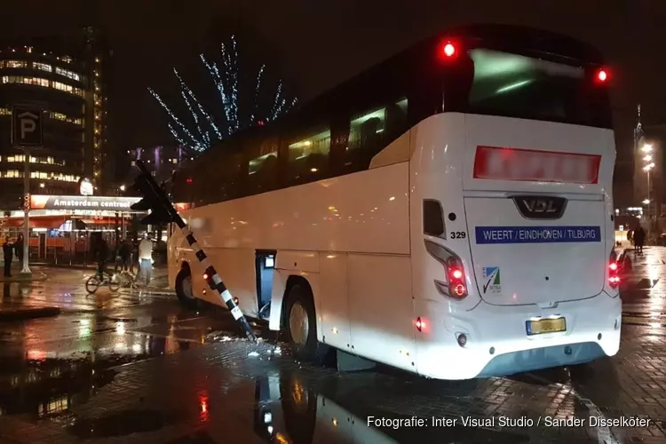 Touringcar rijdt verkeerslicht uit de grond bij Centraal Station in Amsterdam